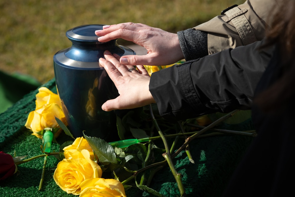 couple putting their hands on a black urn with yellow flowers surrounding them