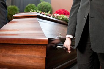 A Well-Dressed Man Holds a Wooden Casket in His Hands, Displaying a Solemn and Serious Demeanor - Funeral Service in Holtze NT